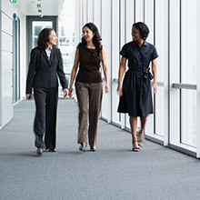 Three women walking down an office hallway