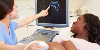 Medical personnel and pregnant patient looking at ultrasound