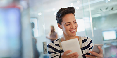 Smiling woman holding tablet and smartphone
