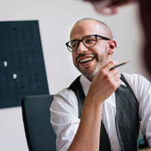 Smiling bearded man wearing spectacles and holding pencil